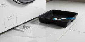 LG 트롬 세탁기 배수 필터에서 물이 새어 나와 바닥이 젖어 있는 모습